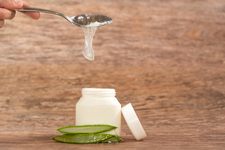 person placing Aloe Vera pulp in a plastic container with a metal spoonの写真素材