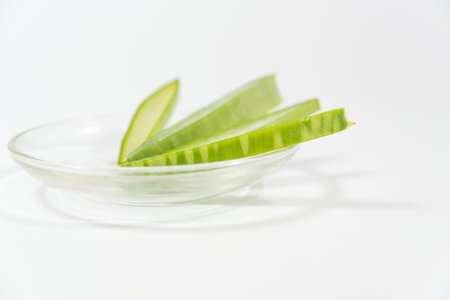 Aloe Vera leaf cut into pieces in a glass container on a wooden tableの写真素材