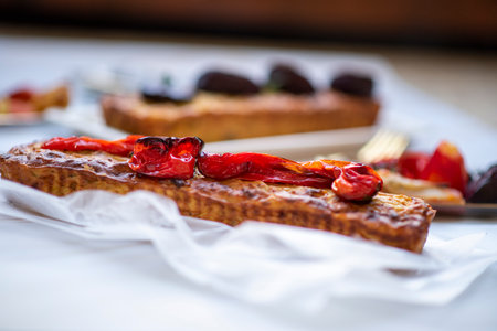 Homemade healthy salted cake with roasted red peppers and beets on top. Rectangular shapes on a white marble background. Glass saucers, gold cutlery, and a towelの写真素材
