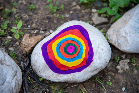 Pebbles with a painted flower on the background of a cooperative and community ecological gardenの写真素材