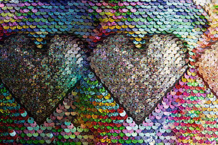 A pattern of glittering colored sequins form a heart shape