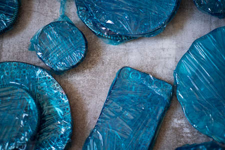 Small plates wrapped in blue cling film placed on brown wooden floor background. Top view. Copy Spaceの写真素材