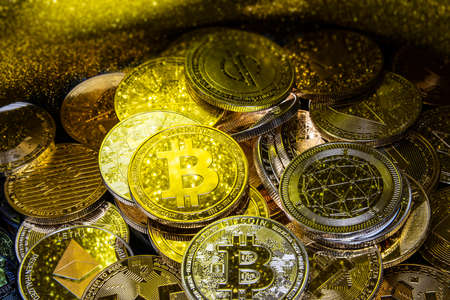 Horizontal view of cryptocurrency tokens, including Bitcoin, Ethererum Ripple, and Litecoin saw from above on a yellow gold backgroundの写真素材
