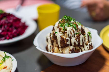 One whole head of roasted cauliflower with roasting ingredients and tahini sauce. Middle Eastern Health Diet. Mediterranean and Balkan food.の写真素材