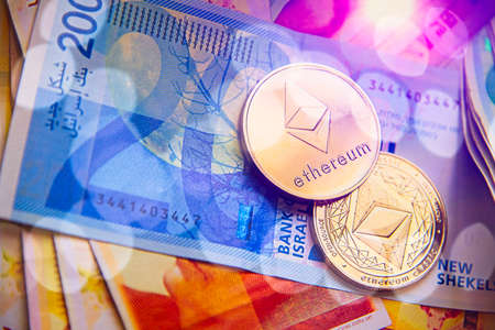 Horizontal view of cryptocurrency token Ethereum etc bitcoin saw from above on Israeli Shekel ILS background.のeditorial素材