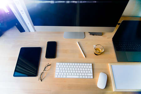 Close up of working place in an office with wooden table and laptop laying, Place of work. a comfortable working place with laptop espresso smartphone notepad paper pen eyeglasses mouse laying on it. Hebrew Keyboard. High quality photoの写真素材