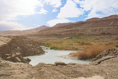 Sinkhole filled with turquoise water, near Dead Sea coastline. Hole formed when underground salt is...