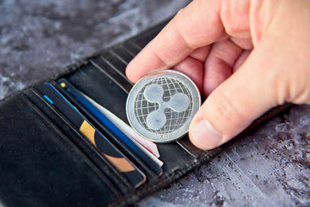 Crypto coin, XRP Ripple coin in leather wallet on concrete style background with clipping path. Hand holding a Coin. Cryptocurrency business concept.のeditorial素材