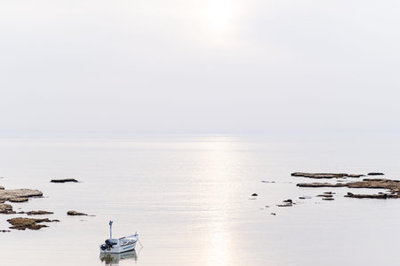 A small fishing boat on the beach in Jaffa, on a foggy day. Concept for peace, quiet and serenity. High key photographyの写真素材
