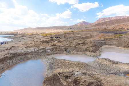 Sinkhole filled with turquoise water, near Dead Sea coastline. Hole formed when underground salt is...