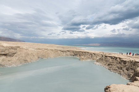 Sinkhole filled with turquoise water, near Dead Sea coastline. Hole formed when underground salt is dissolved by freshwater intrusion, due to continuing sea-level drop.の写真素材