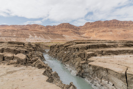 Sinkhole filled with turquoise water, near Dead Sea coastline. Hole formed when underground salt is...