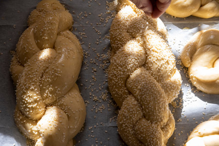 Baking homemade challah bread. A braid with sesame seeds in a pan before baking