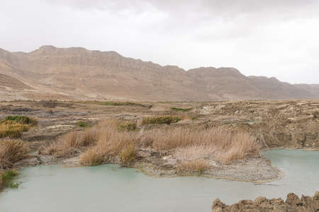 Sinkhole filled with turquoise water, near Dead Sea coastline. Hole formed when underground salt is dissolved by freshwater intrusion, due to continuing sea-level drop.の写真素材