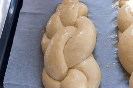 Baking homemade challah bread. A braid with sesame seeds in a pan before baking