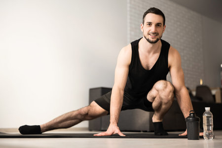 Sporty man doing side lunge exercise. Male athlete with fit body warming up, doing leg stretch...