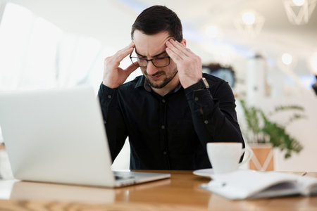 It doesnt work Tired male programmer massaging temples, holding head and looking for an error in the code. Remote or freelancer worker drinking coffee in cafe.の写真素材