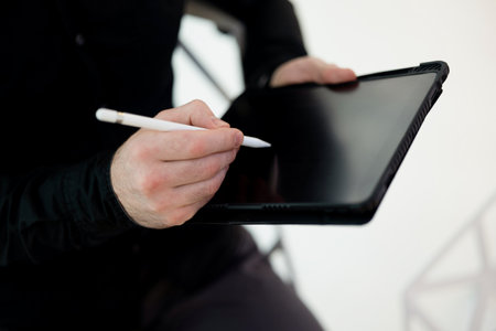Copy space screen of tablet. Close up shot of male hands signing on gadget using stylus. Cut view of man in dark clothes. Dont recklessly sign e-invoices Financial literacy concept.の写真素材