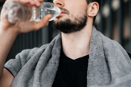 Man drinking water from plastic bottle after hard workout. Close up cut view of male face. Dont forget to drink during training. Take care of youself concept. Drink more water. Hydration timeの写真素材