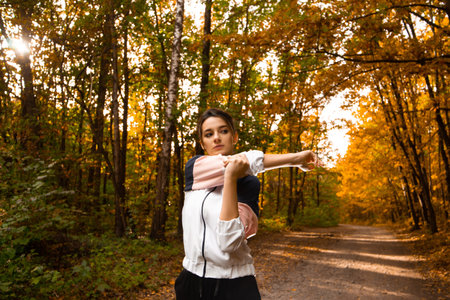 Female athlete warming up before hard workout. Healthy lifestyle. Fitness sporty woman stretching before run early in the morning in forest area. Sunshine on background.の写真素材