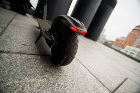 Close up scooter wheel. Convenient way to travel. Concrete plates after rain. Big city on...
