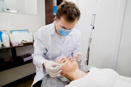 Dermatologists putting nutrition cream on the young and beautiful woman skin to make her skin smooth and healthy.の写真素材