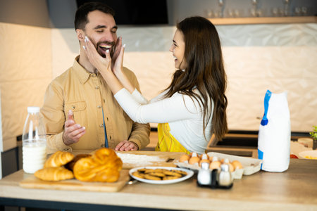 Couple is having fun while cooking. They look happy being together in the kitchen together. They are baking some cookies and bunsの写真素材