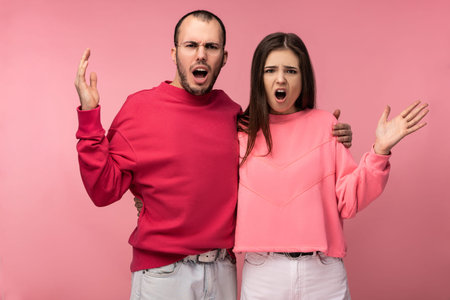 Photo of attractive man wih beard in red clothing and woman in pink are dreadly sorehead, isolated...