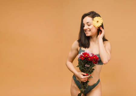 Close up fit and sporty female in underwear. Beautiful and healthy woman posing over beige background. Sport, fitness, diet, weight loss and healthcare conceptの写真素材