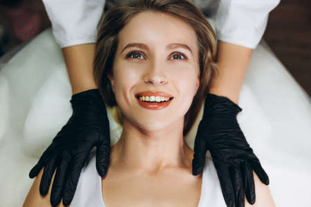 Facial massage beauty treatment. Closeup of a young woman s face lying on back, getting face lifting massage, pinch and roll techniqueの写真素材