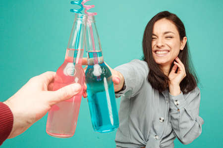 Photo of attractive lady drinks cocktails. Wears grey shirt, isolated turquoise color backgroundの写真素材