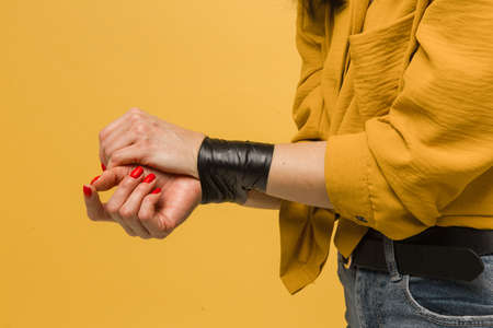 Concept close up photo of female victim with her mouth taped up, kidnapping. Wears yellow shirt, isolated yellow color backgroundの写真素材