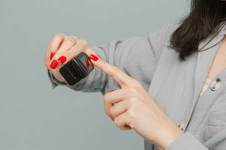 Close up photo female in face mask with pulse oximeter on her finger, checks her health. Wears grey dress, isolated grey color backgroundの写真素材
