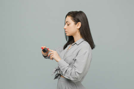 Photo female with pulse oximeter on her finger, checks her health. Wears grey dress, isolated grey color backgroundの写真素材