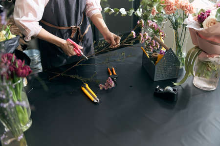 Woman sales flowers in flower shop. Florist woman working at flower shop. Portrait of successful modern florist wearing apronの写真素材