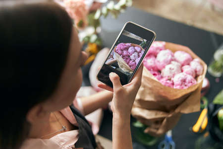 Close up photo florist at work. woman making photo of spring floral decorations.の写真素材