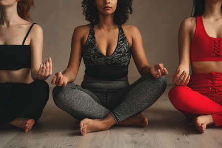 Fit athletic women doing yoga, self control. Beautiful women working out in gym together. Intense fitness training workout in loft industrial gymの写真素材