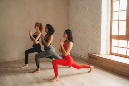 Fit athletic women doing Yoga, healthy lifestyle. Beautiful women working out in gym together. Intense fitness training workout in loft industrial gymの写真素材