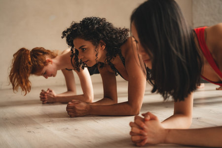 Fit athletic women doing plank, healthy lifestyle. Beautiful women working out in gym together. Intense fitness training workout in loft industrial gymの写真素材