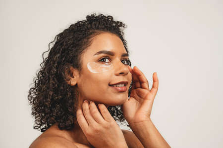 Close up photo of face attractive black woman with patches under eye. Isolated over white background. Natural beauty and healthの写真素材