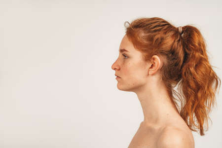 Close up face in profile natural redhead cute woman with freckles. Isolated over white background. Natural beauty and healthの写真素材