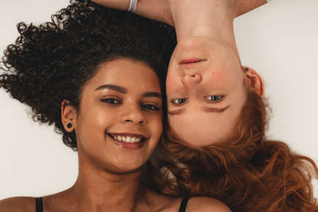 Photo of natural multiracial women, body positive. Feminist females lay down, isolated on white background. Concept natural beauty and girl powerの写真素材
