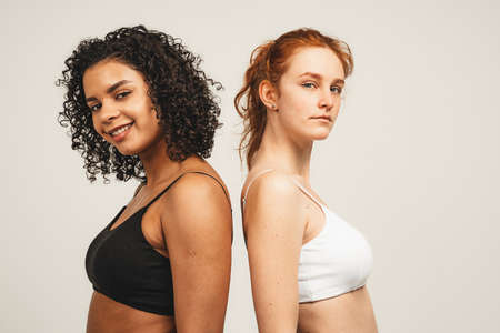 Photo of natural multiracial women, body positive. Feminist females in underwear stand back to back, isolated on white background. Concept natural beauty and girl powerの写真素材