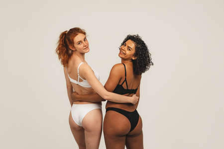 Photo of natural multiracial women, body positive. Feminist females in underwear hug each other, isolated on white background. Concept natural beauty and girl powerの写真素材