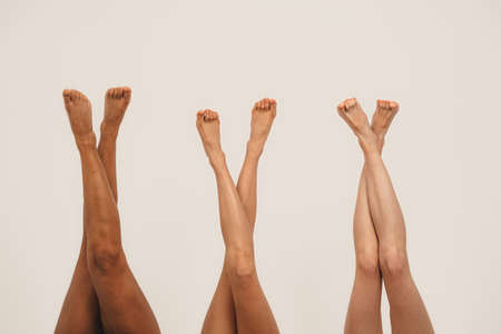 Photo of young women legs, multiracial friends. Isolated on white background. Concept natural beauty and girl powerの写真素材