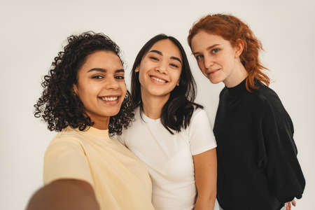 Photo of optimistic cheery young women, multiracial friends make selfie. Concept natural beauty and girl powerの写真素材