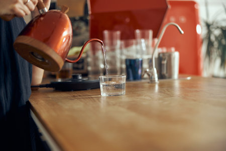 Professional barista pours water, hands close-up. Pouring water in glassの写真素材