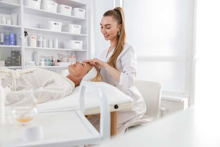 Senior female is lying on back, getting face lifting massage. Facial massage beauty treatment. Wellness, beauty and relaxation conceptの写真素材