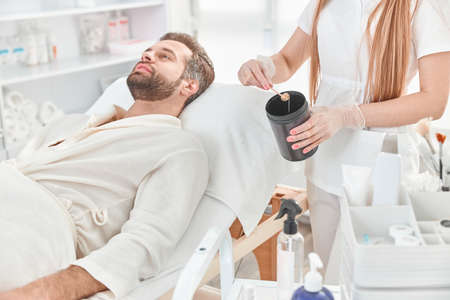 Cosmetologist takes sugar paste from can in wax. Concept of medicine, medical instruments, health care, beauty industry, hair removalの写真素材