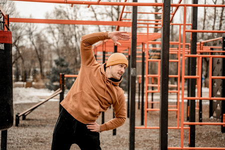 Young man in sports outfit doing morning workout outdoors. Young man stretching his muscle before...